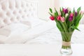 Home interior with pink tulips in a vase on a light bedroom background Royalty Free Stock Photo