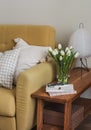 Home interior. A yellow sofa, a wooden bench with a paper lamp, a bouquet of tulips in a vase, a magazine in the living room Royalty Free Stock Photo