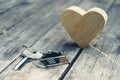 Home key with house keychain and wooden heart mock up on vintage wood background, home sweet home concept Royalty Free Stock Photo