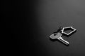 Home key with house keyring on black wood table in dark tone, real estate concept