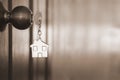 Home key with house keyring in keyhole on wooden door Royalty Free Stock Photo