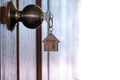 Home key with house keyring in keyhole on wooden door Royalty Free Stock Photo