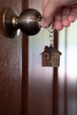 Home key with house keyring in keyhole on wooden door Royalty Free Stock Photo