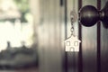 Home key with house keyring in keyhole on wooden door Royalty Free Stock Photo