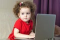 Home, leisure, games, online learning, technology and internet concept - little serious girl with laptop at home. Royalty Free Stock Photo