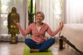 Home lifestyle - beautiful and happy mature woman with gray hair on her 50s doing yoga and meditation exercise at Asian deco Royalty Free Stock Photo