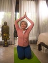 Home lifestyle - beautiful and happy mature woman with gray hair on her 50s doing yoga and meditation exercise at Asian deco Royalty Free Stock Photo