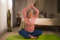 Home lifestyle - beautiful and happy mature woman with gray hair on her 50s doing yoga and meditation exercise at Asian deco Royalty Free Stock Photo