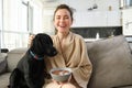 Home and lifestyle concept. Beautiful young woman with dog, sitting on sofa, eating cereals and hugging her puppy, girl Royalty Free Stock Photo