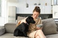 Home and lifestyle concept. Beautiful young woman with dog, sitting on sofa, eating cereals and hugging her puppy, girl Royalty Free Stock Photo