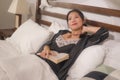 Home lifestyle morning portrait of young beautiful and happy Asian Chinese woman in nightgown reading a book in bed enjoying the Royalty Free Stock Photo