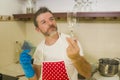 Home lifestyle portrait of happy and attractive man in red apron smiling at kitchen washing dishes and wine glass doing housework Royalty Free Stock Photo