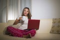 Home lifestyle portrait of young attractive and natural Asian hispanic woman in pajamas pants relaxed on couch networking using Royalty Free Stock Photo