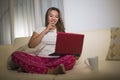 Home lifestyle portrait of young attractive and natural Asian Indonesian woman in pajamas pants relaxed on couch networking using Royalty Free Stock Photo