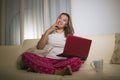 Home lifestyle portrait of young attractive and natural Asian Indonesian woman in pajamas pants relaxed on couch networking using Royalty Free Stock Photo