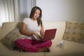 Home lifestyle portrait of young attractive and natural Asian Indonesian woman in pajamas pants relaxed on couch networking using Royalty Free Stock Photo