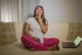 Home lifestyle portrait of young attractive and natural Asian Indonesian woman in pajamas pants relaxed on couch networking using Royalty Free Stock Photo