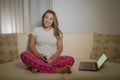 Home lifestyle portrait of young attractive and natural hispanic woman in pajamas pants relaxed on couch networking using laptop Royalty Free Stock Photo