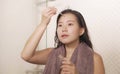 Young beautiful and happy Asian Korean woman applying serum facial skin care and face treatment in the bathroom enjoying morning