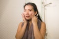 Young beautiful and happy Asian Korean woman applying serum facial skin care and face treatment in the bathroom enjoying morning