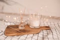 Home liquid fragrance in glass bottle with wooden bamboo sticks and scented candle on tray over glow lights closeup. Home decor. Royalty Free Stock Photo