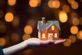 Home loan concept illustrated by hand holding paper house on bokeh background Royalty Free Stock Photo