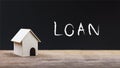 Home loan, house mortgage concept. A small house model on wooden table with chalkboard background Royalty Free Stock Photo