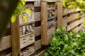 Home made bee hotel, in Dutch garden, mounted on a typical wooden garden fence. Bee hotels are places for solitary bees to make Royalty Free Stock Photo