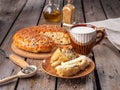 Home-made bread in a cut and a slice of sliced bread smeared with butter and a mug of milk on a plank rustic table, next to wooden Royalty Free Stock Photo