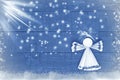 Home made Christmas paper angel on blue, snowy wooden background.Craft