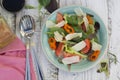 Home made fresh salad with parmezan cheese, greens and tomato. White rustic wooden table. Top view