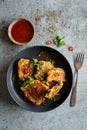 Home made Indonesian corn fritters (Perkedel Jagung or Bakwan Jagung) served with sweet chilli sauce on black plate