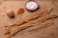 Home made paprika pasta on a cutting board with an egg, powder p