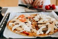 Home made pizza. Person putting cheese, tomato, mozzarella on dough with ketchup, chicken and mushrooms on modern white kitchen. Royalty Free Stock Photo