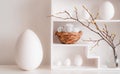 Home minimalist interior with Easter decor. Branches with budding buds in a glass vase on shelves in the shape of a Royalty Free Stock Photo