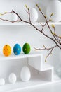 Home minimalist interior with Easter decor. Branches with budding buds in a glass vase on shelves in the shape of a Royalty Free Stock Photo