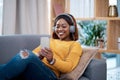 Home is my happy place. an attractive young woman wearing headphones while using her cellphone. Royalty Free Stock Photo