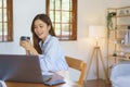 Home office concept, Businesswoman reads marketing plan data of startup on laptop and drinks coffee