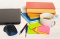 Home office concept. Work from home. Black laptop, books and cafe cuo on the white wooden background. Side view. Sweden.