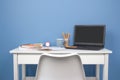 Home office of a creative entrepreneur with black laptop, empty white chair during lunch break. Modern creative workspace with Royalty Free Stock Photo