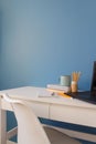 Home office of a creative entrepreneur with black laptop, empty white chair during lunch break. Modern creative workspace with cup Royalty Free Stock Photo