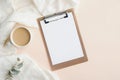 Home office desk with blank clipboard, cup of coffee, blanket and eucalyptus leaf. Modern feminine workspace, minimal style. Flat Royalty Free Stock Photo