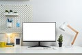 Home office desk with blank computer monitor, picture frame, lamp and peg board on wall Royalty Free Stock Photo