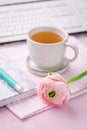 Home office desk with cup of tea, flower, keyboards and writing supplies