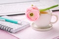 Home office desk with cup of tea, flower, keyboards and writing supplies