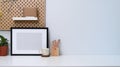 Home office desk with empty photo frame, cup, house plant and pencil holder. Royalty Free Stock Photo