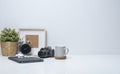 Home office desk with empty picture frame, camera, coffee cup and potted plant on white table. Copy space for your advertise text Royalty Free Stock Photo