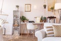 Home office desk with oldschool telephone, typewriter and fresh plants placed in white living room interior Royalty Free Stock Photo
