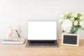 Home office desk table with laptop computer with blank white screen, supplies, picture frame, feminine accessories and flowers Royalty Free Stock Photo