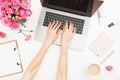 Home office desk. Woman workspace with female hands, laptop, pink roses bouquet, accessories, diary on white. Top view. Flat lay. Royalty Free Stock Photo